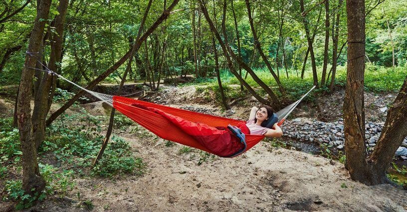 Person schaukelt in einer Hängematte im Wald